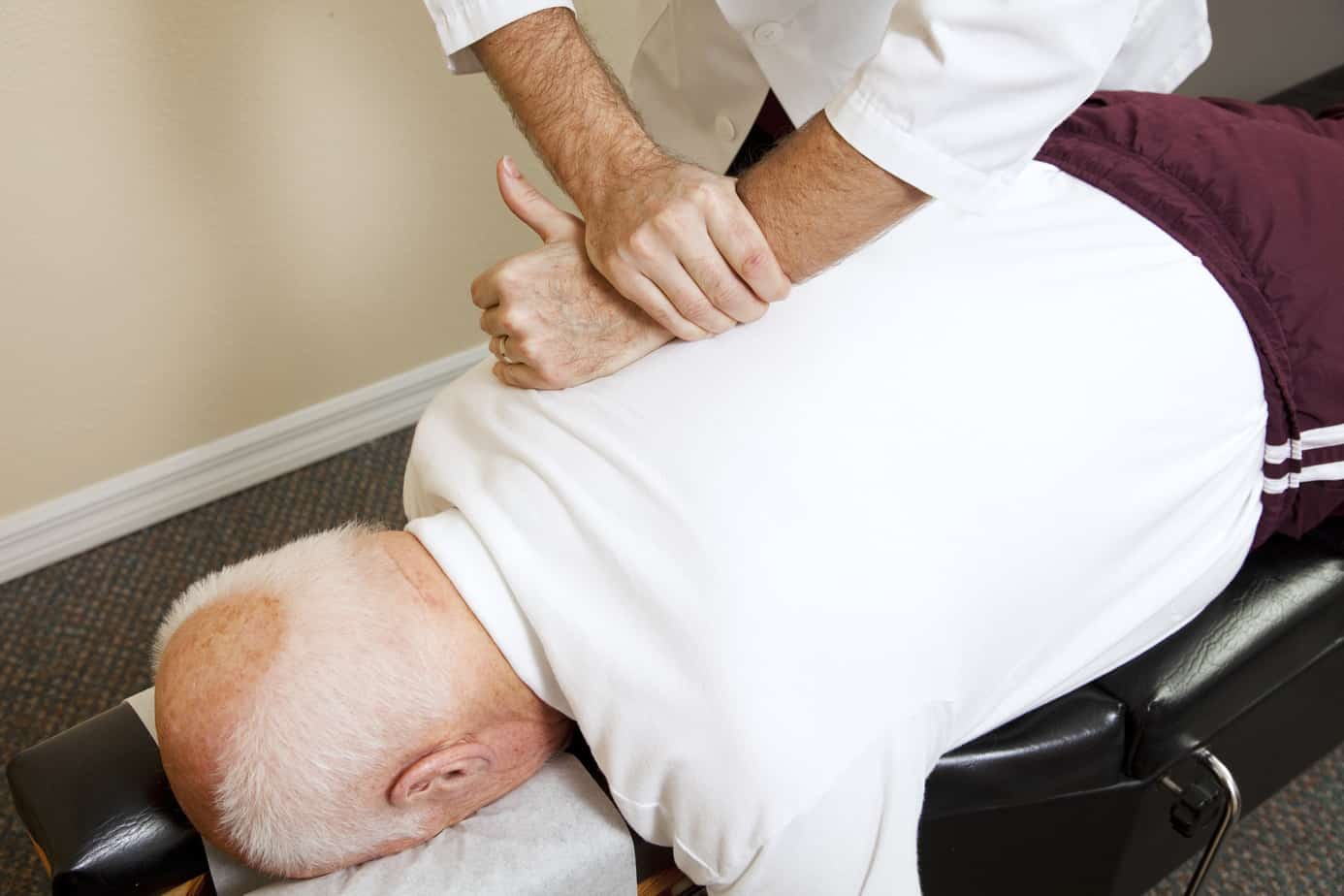 man in white shirt laying face down recieving senior chiropractic care